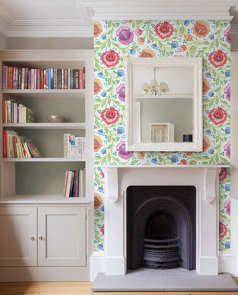 Living room shot with a chimney breast that features colourful floral wallpaper on the wall. The wallpaper has white background and features large red, purple, orange and blue flowers.