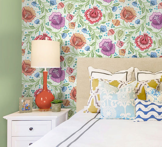 Bedoom shot with colourful floral wallpaper on the wall. The wallpaper has white background and features large red, purple, orange and blue flowers.